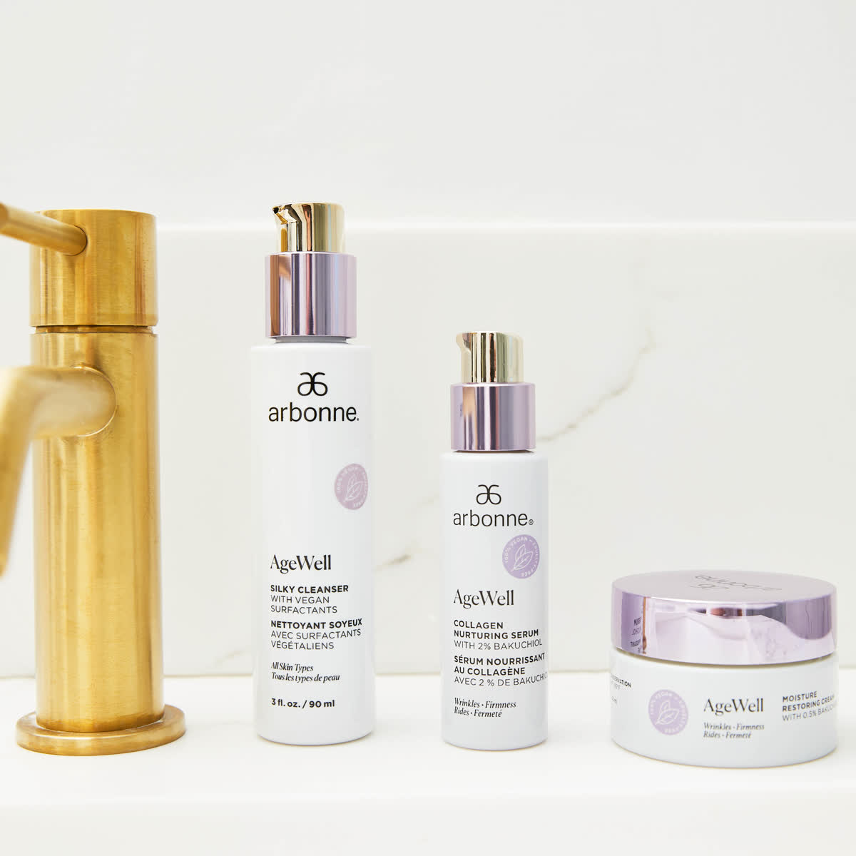 Arbonne AgeWell range lined up beside a brushed gold tap
